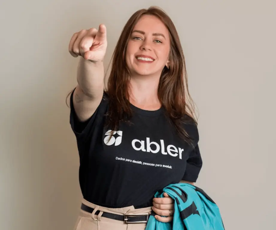 Profissional com camiseta da abler aponta para a frente e sorri